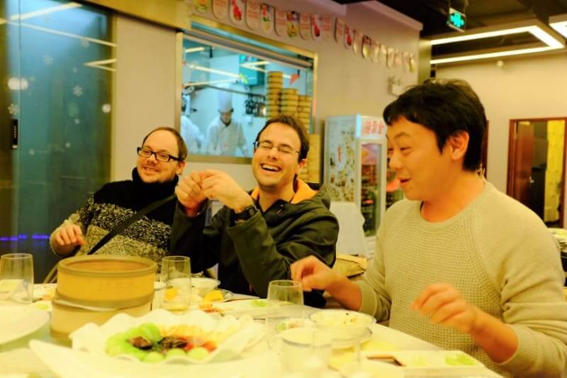 Teachers and students laughing at the table at a Beijing roast duck dinner