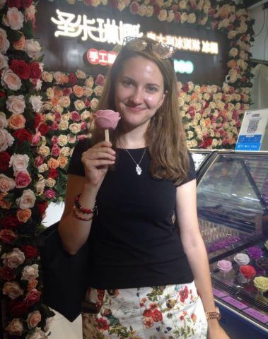 Martina holding a flower shaped ice cream inside a shop in a Beijing Hutong